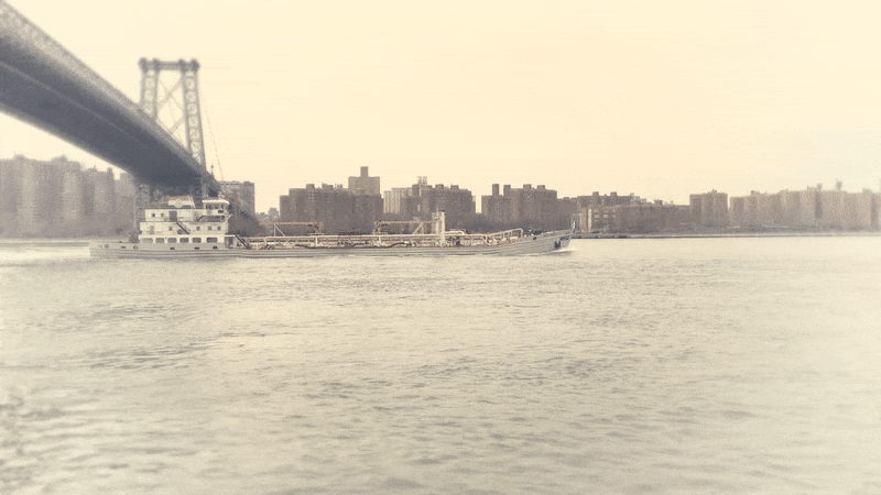 Looping GIF of a large boat going under the Williamsburg bridge